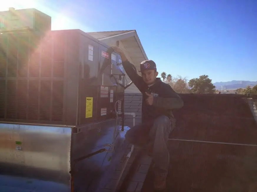 HVAC technician performing Air Duct Cleaning on a rooftop unit in Monmouth